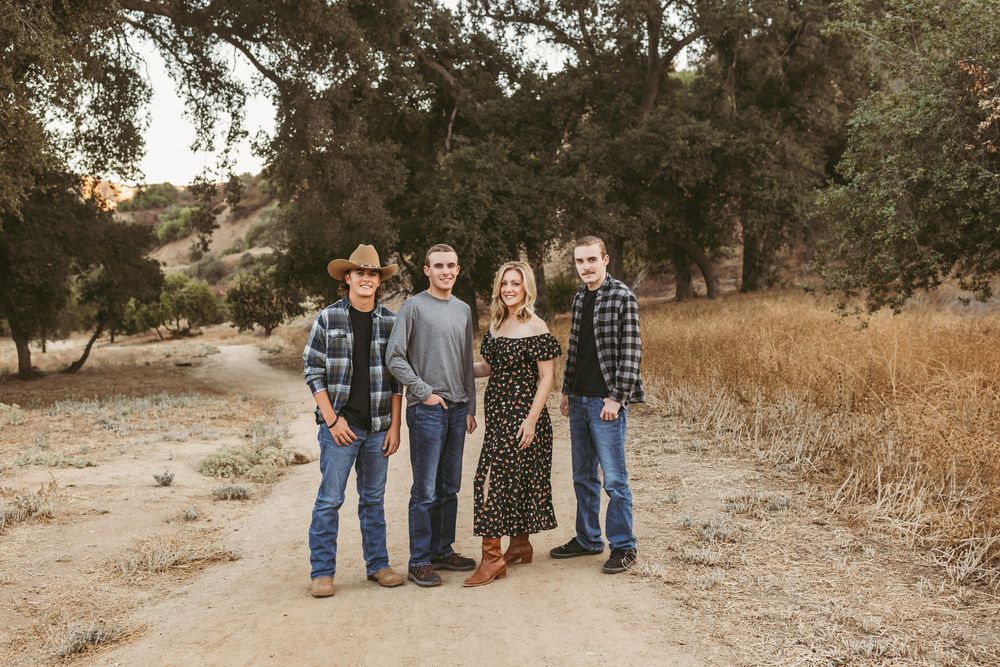A group of people stand together outdoors in casual attire on a dirt path during golden hour.