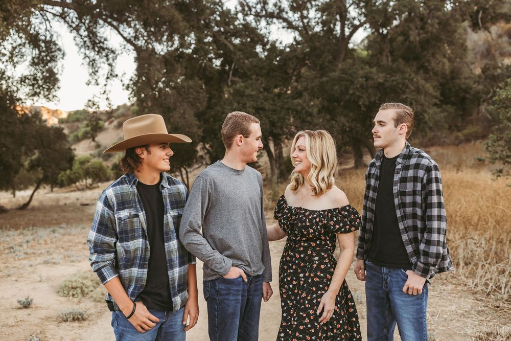 Group of friends in casual western attire laughing together outdoors during golden hour.