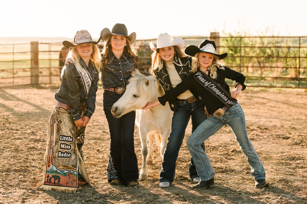 A group poses casually in western wear against a rustic backdrop.