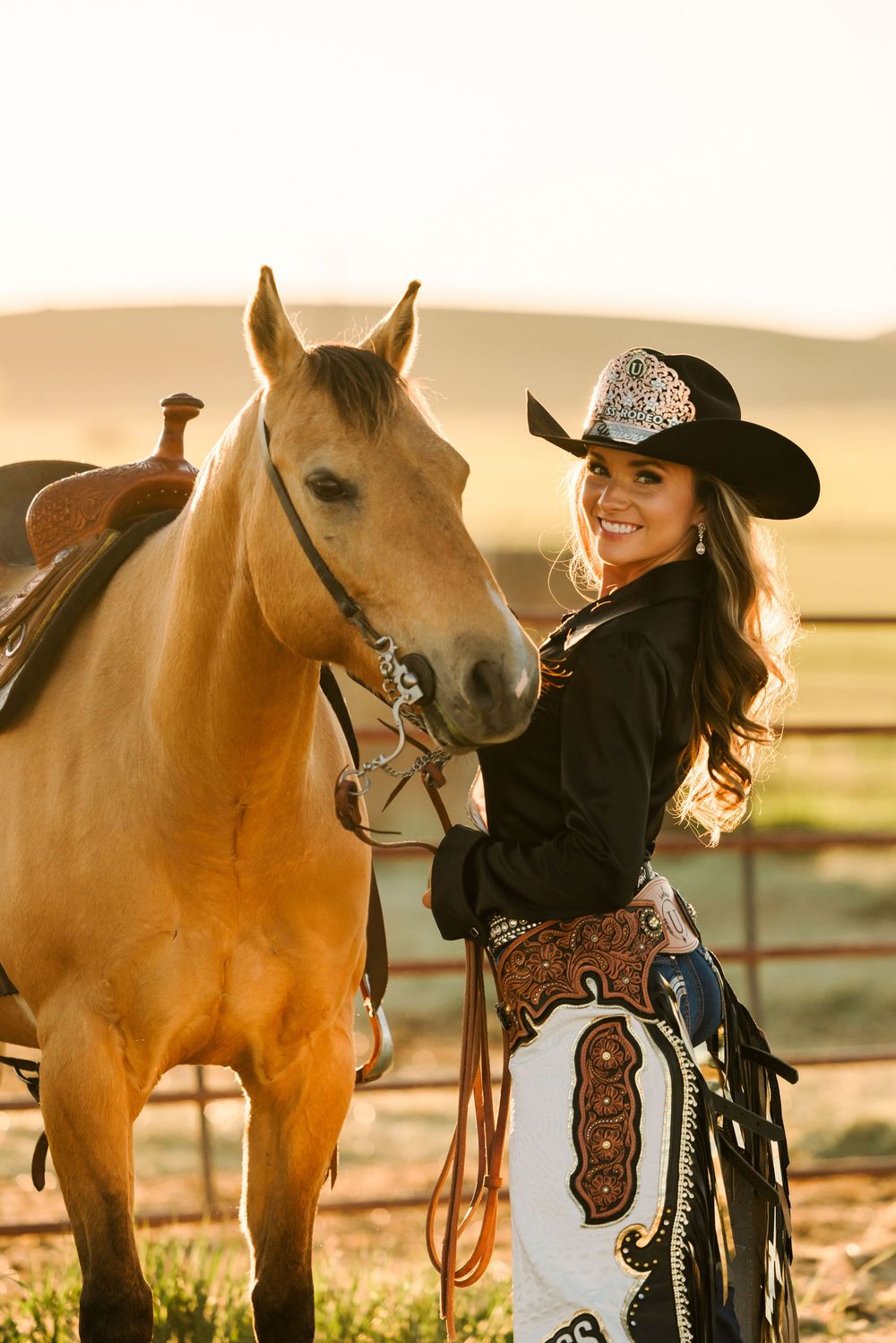 Rider and horse share a tender moment in golden sunlight with rustic fence in background.