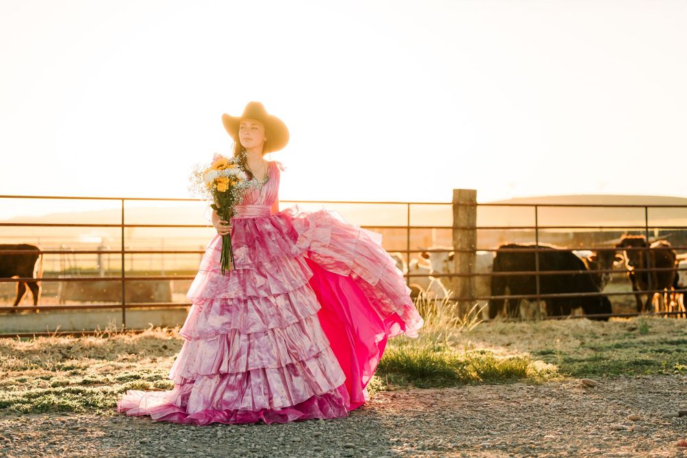 Pink tulle dress flows dramatically in ranch setting during sunset photoshoot.