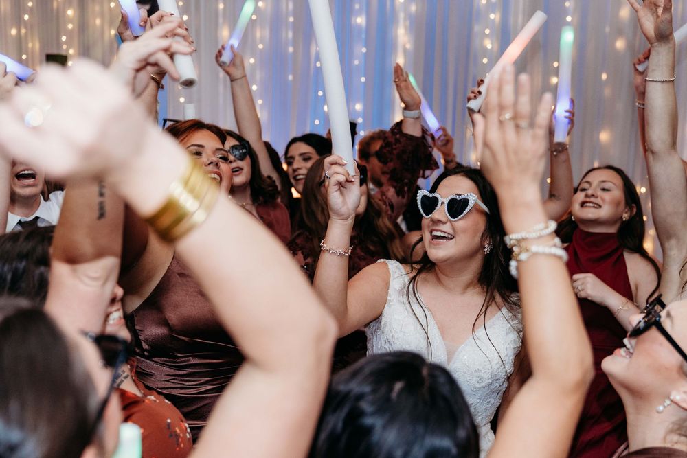 A crowd of energetic people dancing with raised hands at a lively party or concert event.