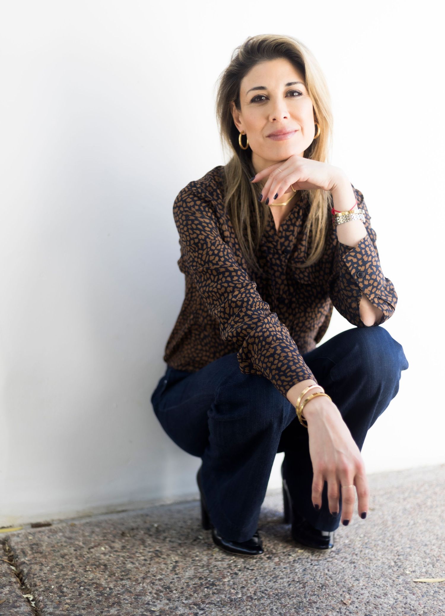 Professional portrait featuring brown animal print blouse and dark jeans.