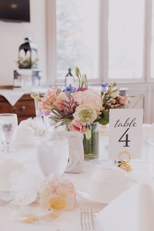 Table 4 wedding centerpiece features pink and white flowers in a glass vase on an elegant white tablecloth.