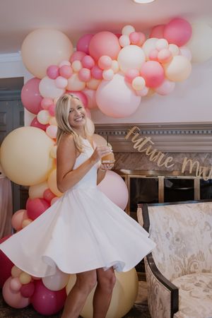 A sequence of photos showing a person in a white dress twirling against a pink and white balloon backdrop.