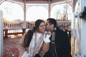 Couple shares intimate moment together on gazebo bench during golden hour sunset.