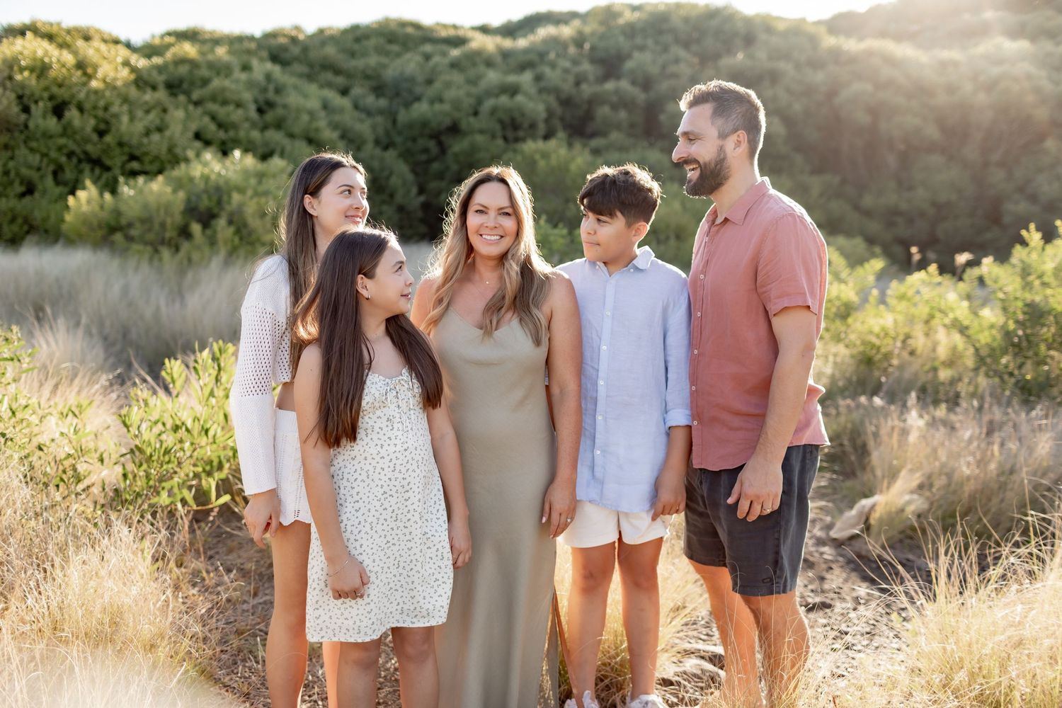 A group of people walk together through a golden meadow during sunset, creating a warm and intimate outdoor scene.
