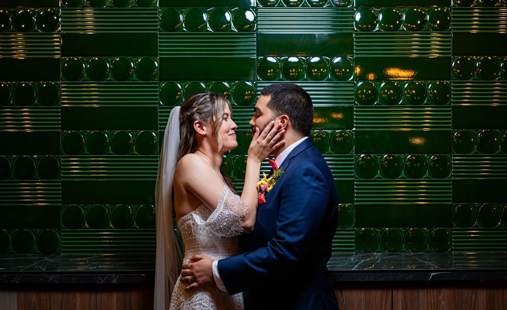 Wedding couple dances elegantly in front of a green illuminated wall with sheet music notation decorations.