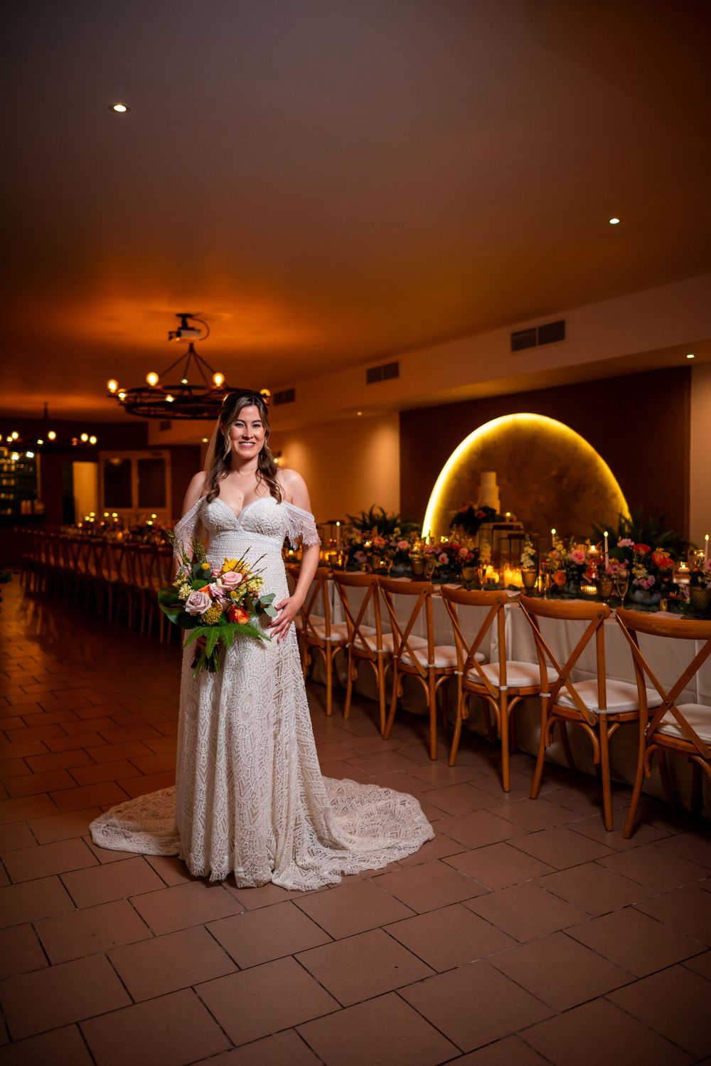 Indoor wedding venue with elegant table settings and warm lighting featuring illuminated golden arch decor.