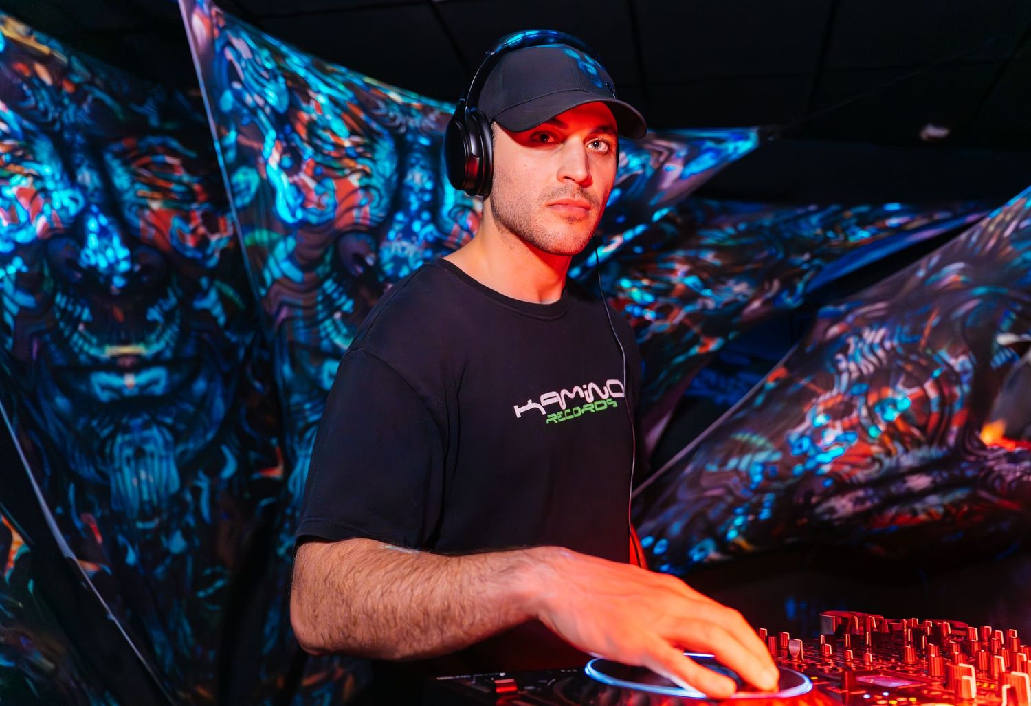 Hi-tech DJ performing in a dark club setting, focused on the mixer, captured with blue light event photography. Master of Puppets MOP teaser