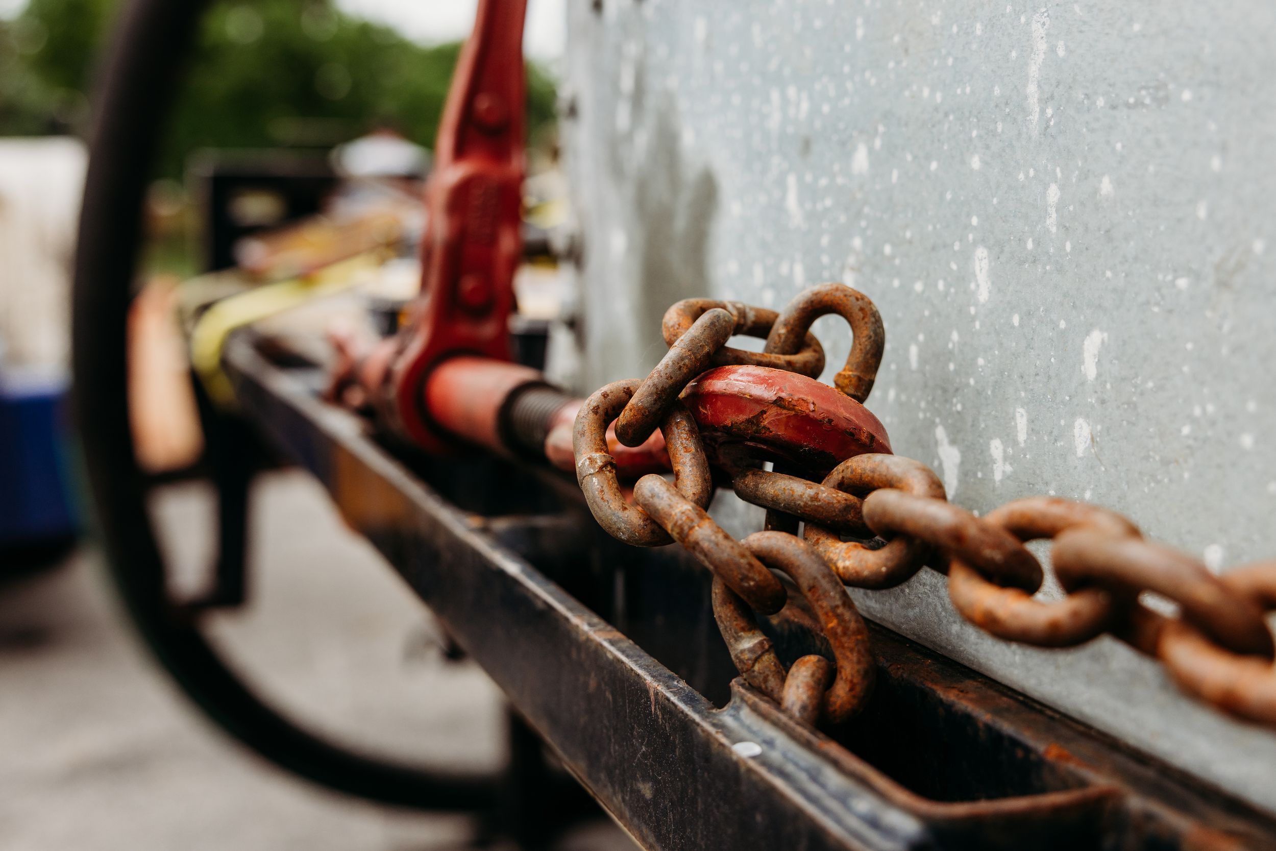 Rusty metal chain links in various states of wear and deterioration create an industrial pattern against a concrete wall.
