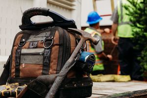 Brown and black travel backpack with gear sitting on ground during outdoor adventure or hiking trip.
