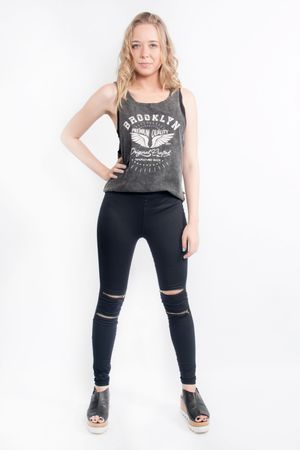 Person wearing a Brooklyn graphic tank top with black distressed leggings and platform sandals against white background.