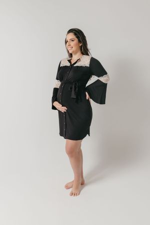 A maternity photo of someone wearing a black and white robe with bell sleeves in a studio setting.