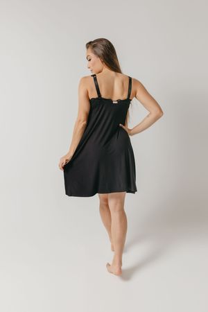 Model wearing a black sleeveless knee-length loungewear dress shown from behind against a light gray background.