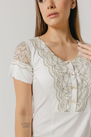 Delicate white blouse with intricate floral embroidery detail and short cap sleeves photographed in studio lighting.