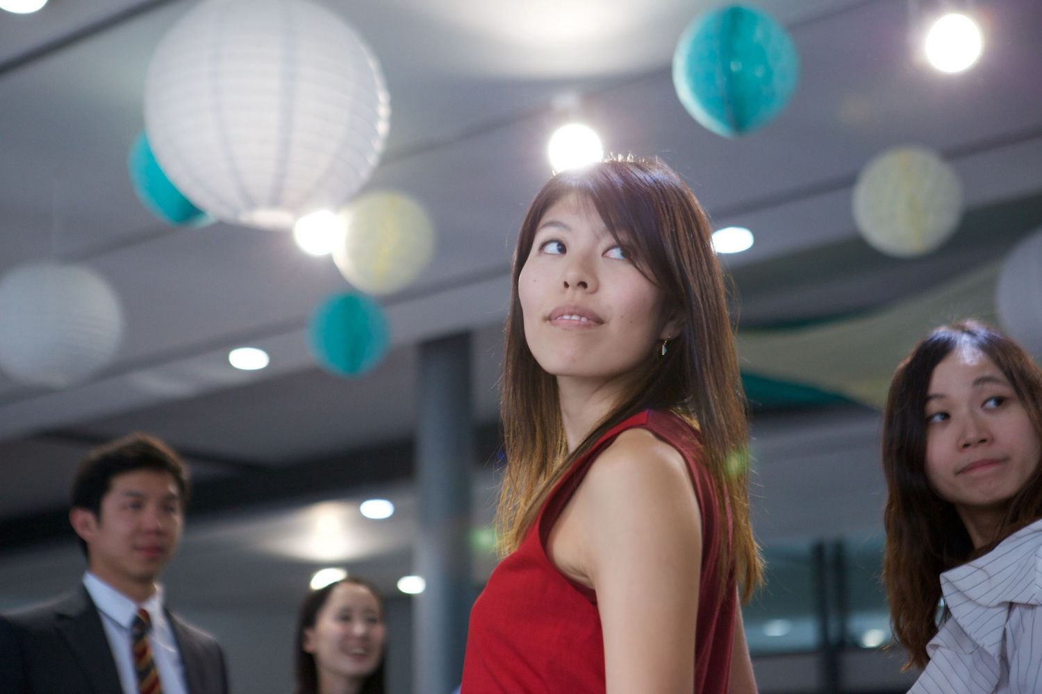 Colorful paper lanterns and decorative balls hang from the ceiling at an indoor celebration or event.
