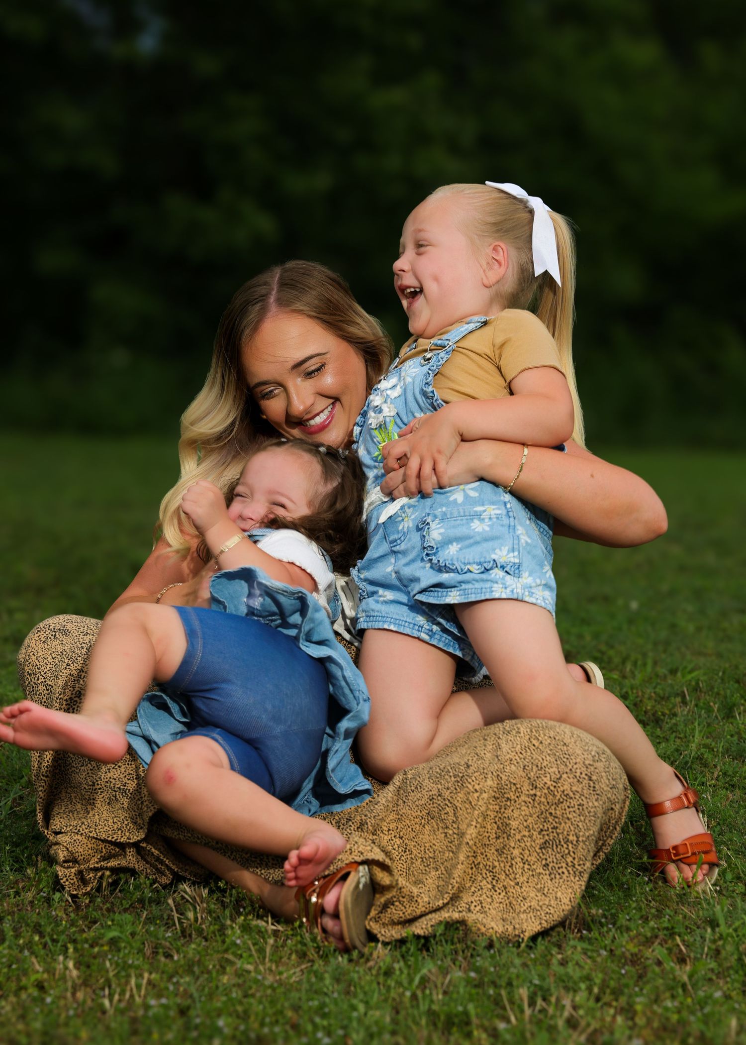 A playful sequence of people rolling and laughing together on green grass during a sunny day outdoors.