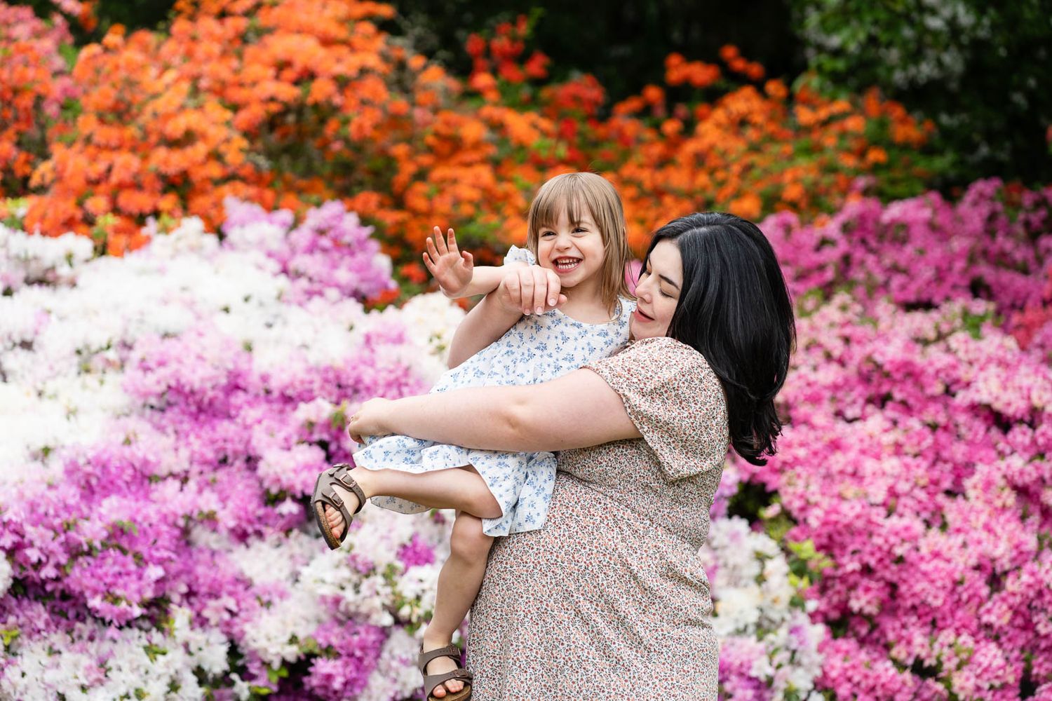 Mom wrangling her daughter in a garden.
