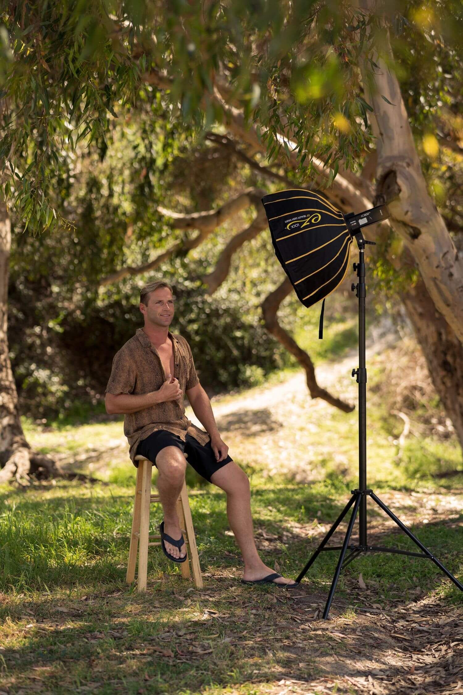 A tripod camera setup stands in a sunlit outdoor setting in san clemente in trees and dappled lighting creating a natural photography scene