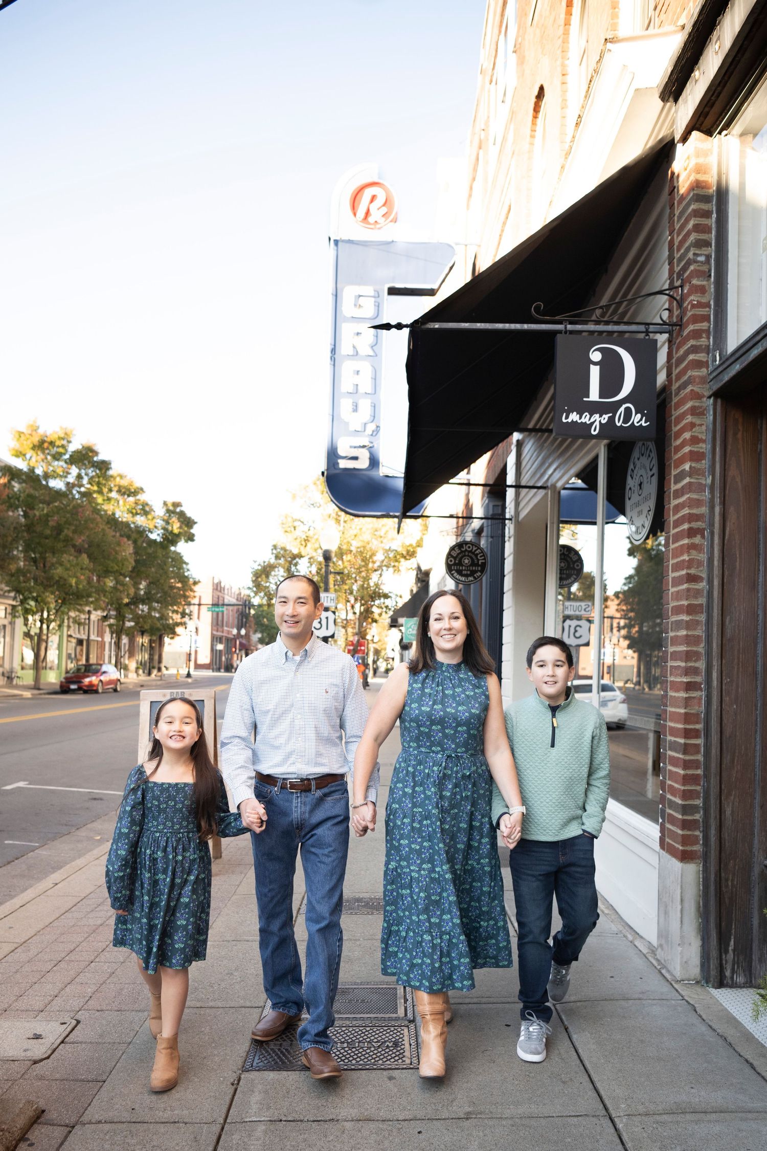 Family of four walking together in downtown Franklin wearing coordinated blue outfits standing in front of Grays.