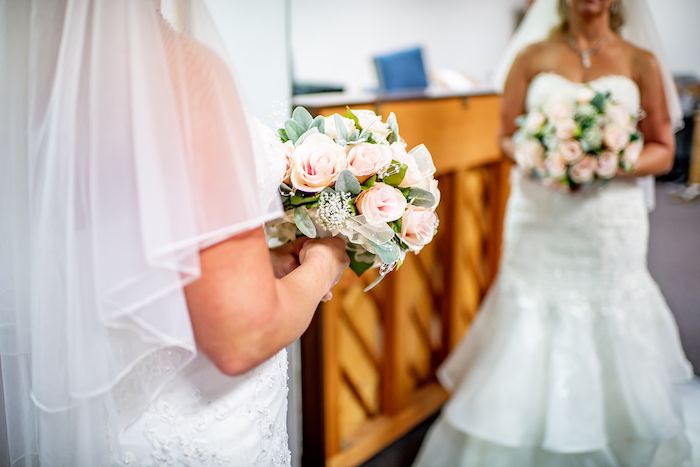 Two wedding bouquets with pink and white roses and floral accents photographed during a bridal ceremony.