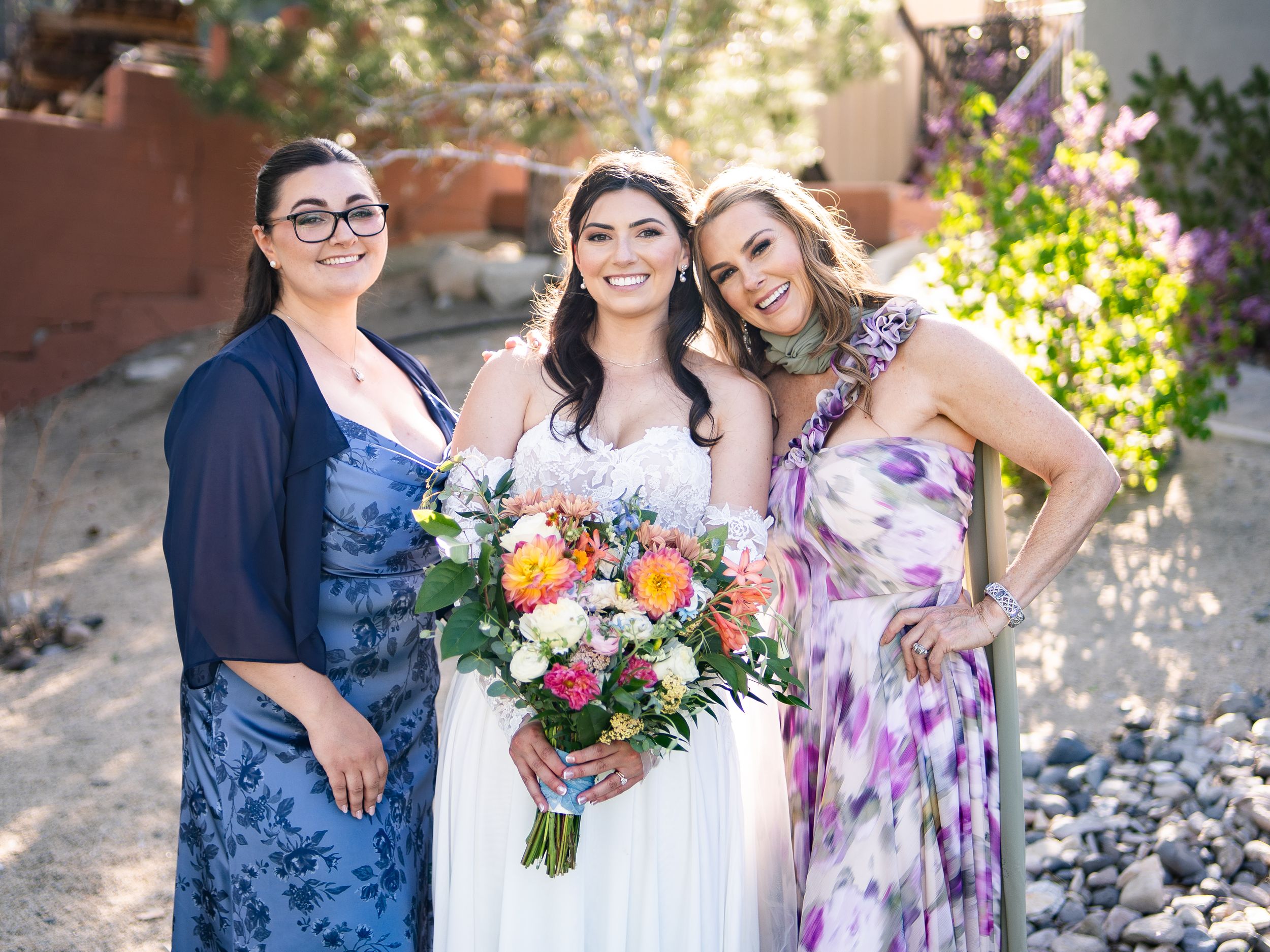 A group in coordinated blue and purple floral outfits poses together outdoors in natural lighting for a special occasion.