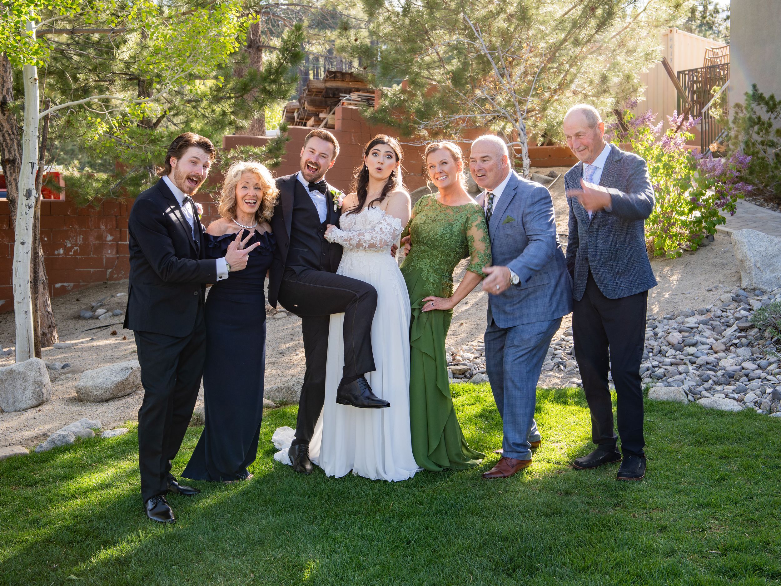 Group of wedding guests on a sunny lawn creating a celebratory party atmosphere in formal attire.