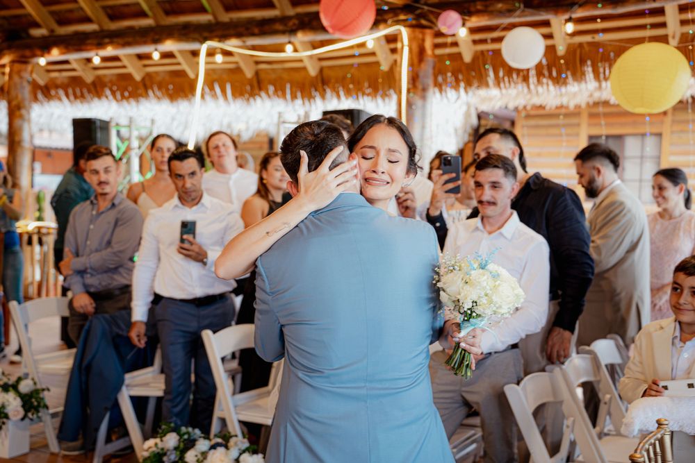 Wedding celebration with colorful lanterns and tiki roof decor in a breezy outdoor beach venue.