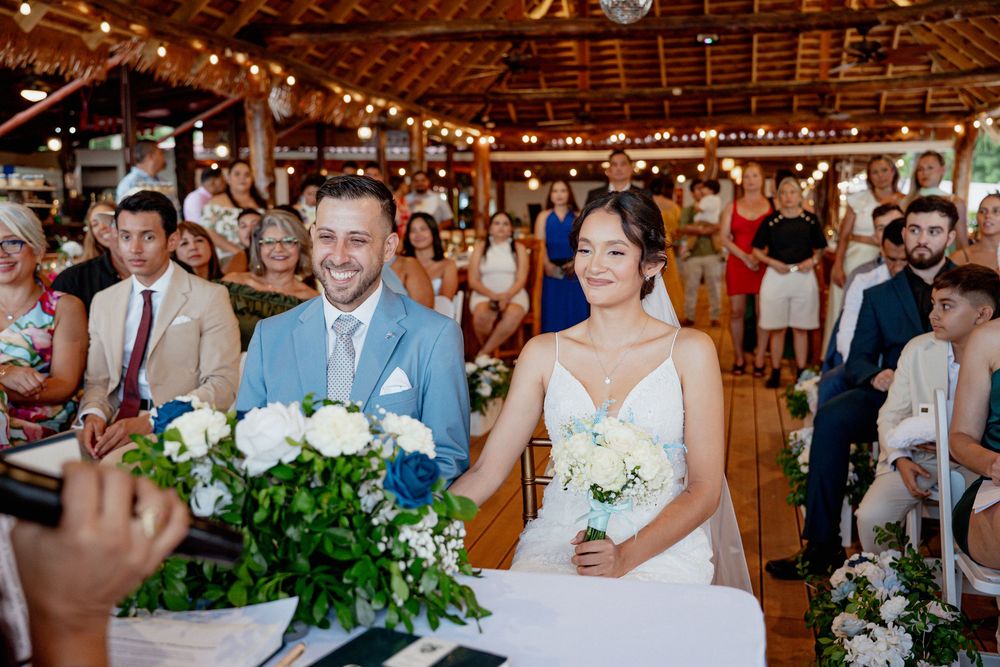 Wedding guests seated in rows under twinkling string lights at an elegant rustic barn reception.