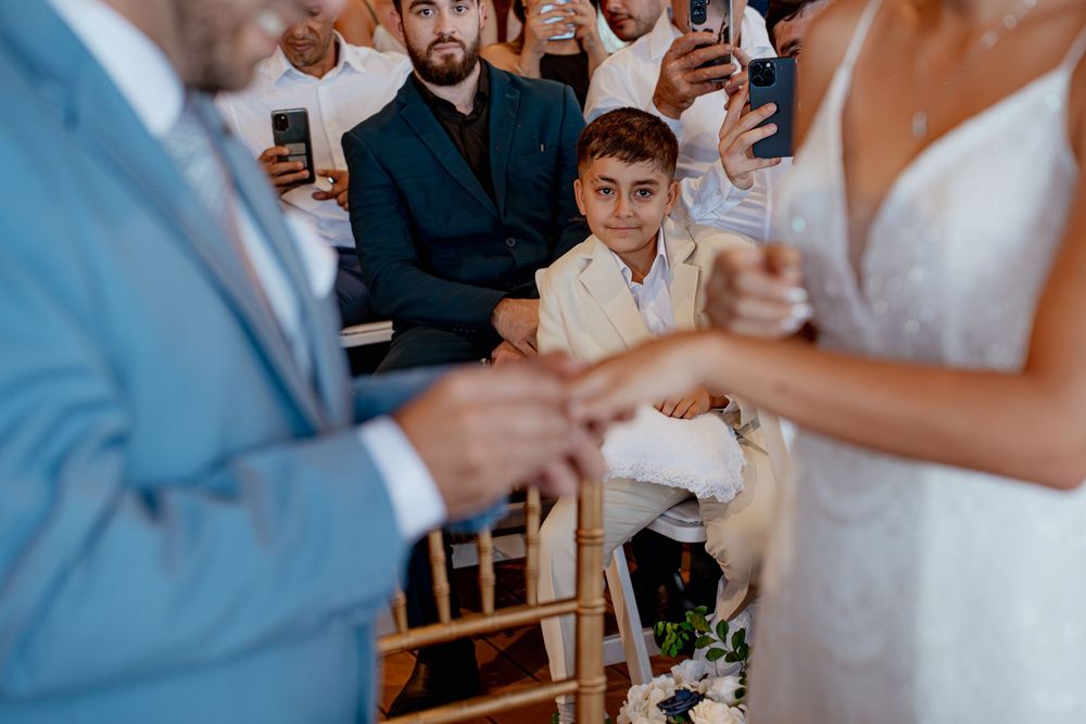 Wedding guests watch the ring exchange ceremony while taking photos on their cellphones during the ceremony.