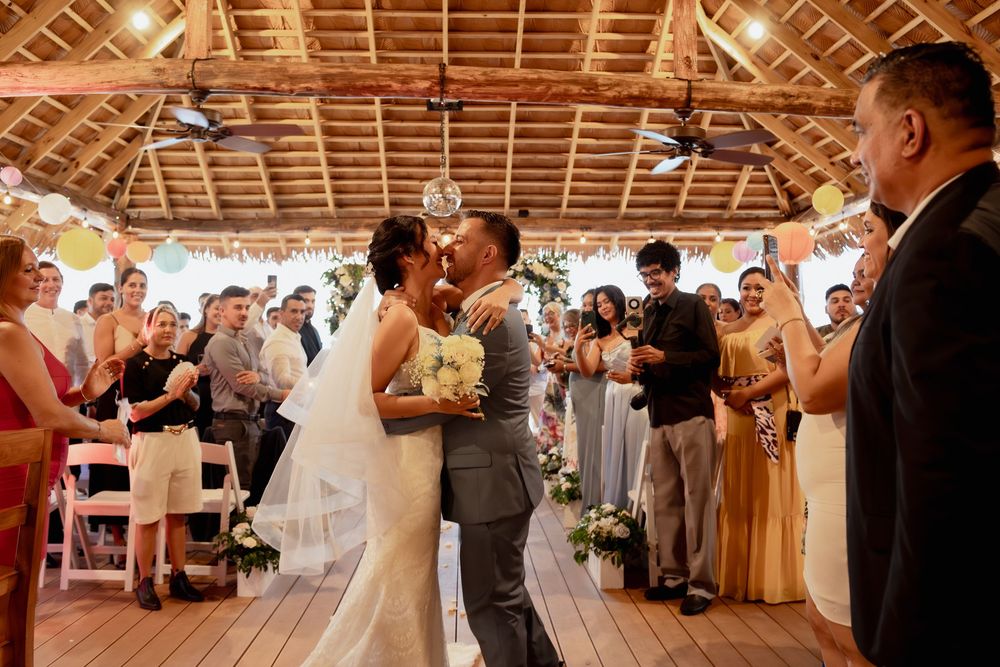 A joyful couple shares their first dance at a rustic barn wedding reception surrounded by cheering guests.