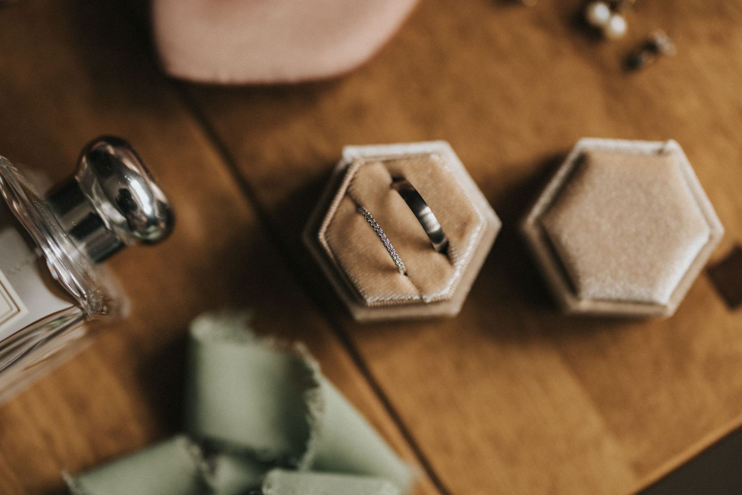 Wedding rings sit elegantly on a brown wooden table next to hexagonal containers and decorative accessories.