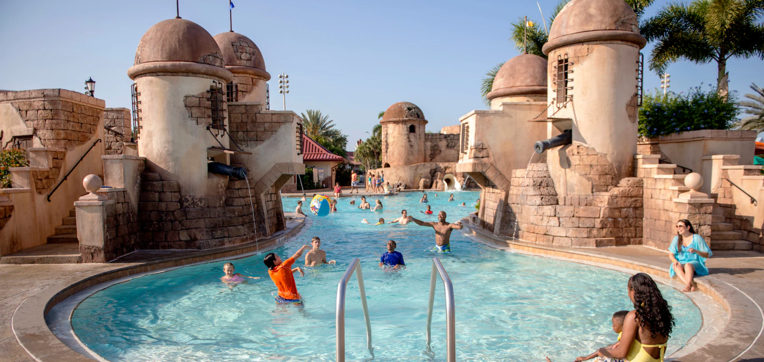 Resort pool with castle-themed turrets and people enjoying the water.