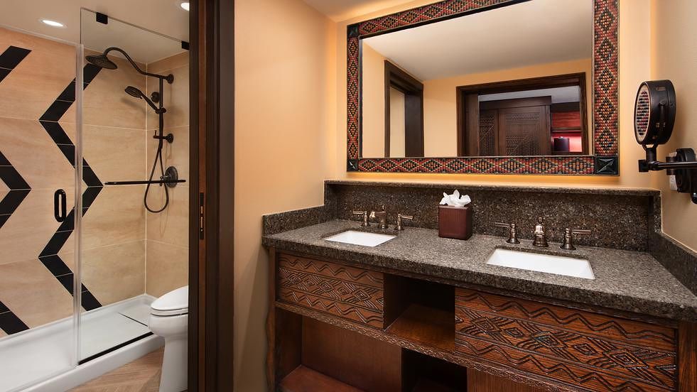 Modern bathroom with chevron shower tile, granite countertop, and dark wood vanity.