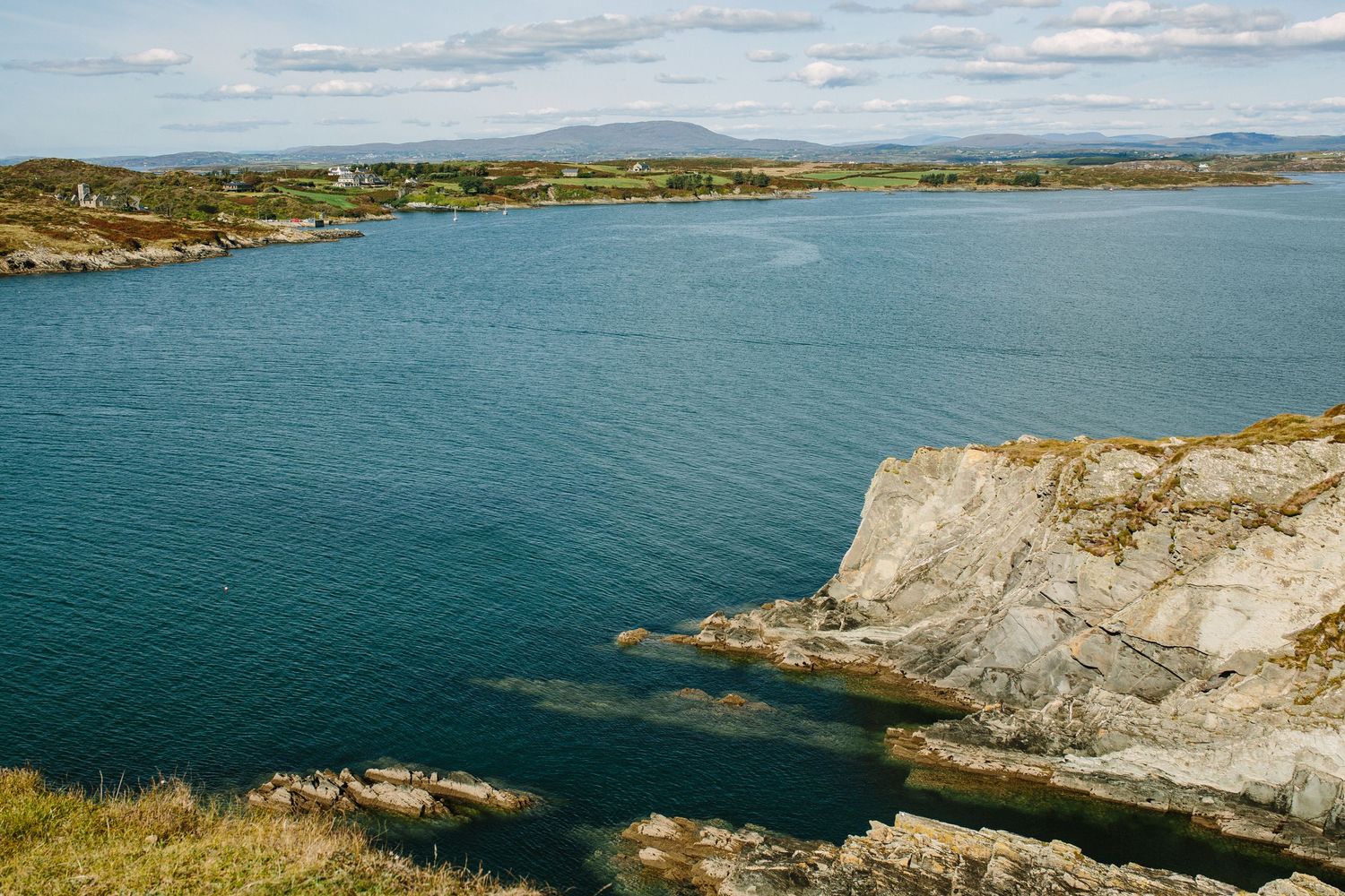 Dramatic coastal cliffs and turquoise waters along the rugged Irish coastline on a sunny summer day.
