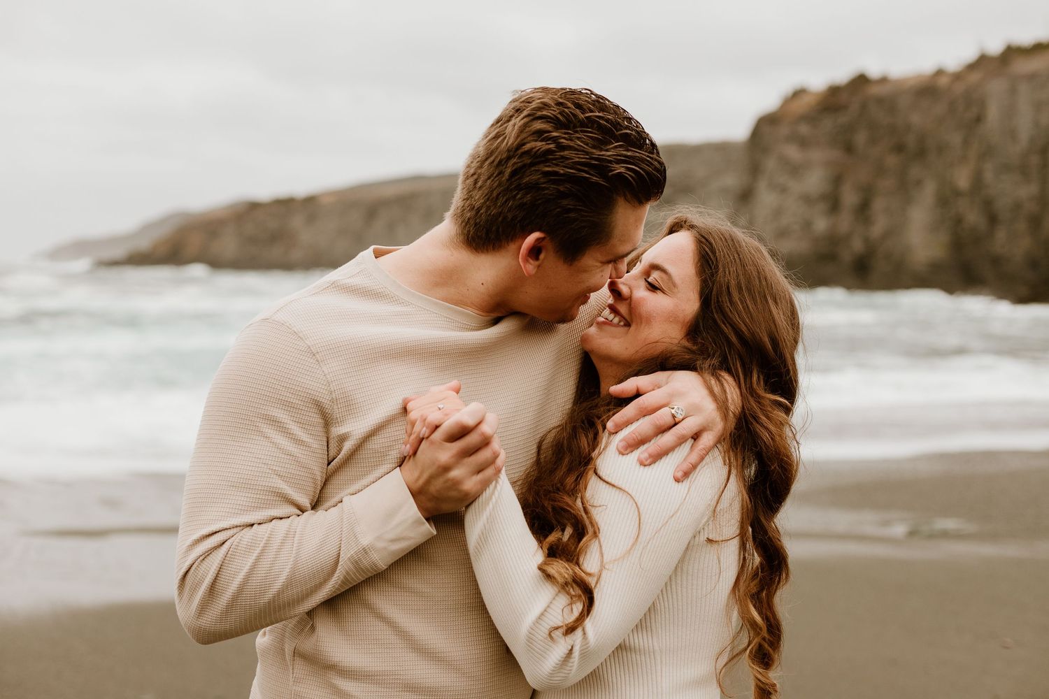 engaged couple holding hands about to kiss during Newfoundland beach session