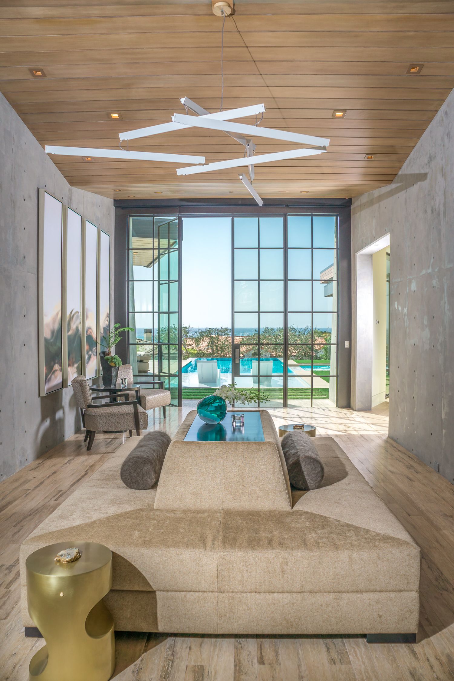 Modern luxury living room with floor-to-ceiling windows, beige sectional sofa, and swimming pool view through glass walls at cameo shores