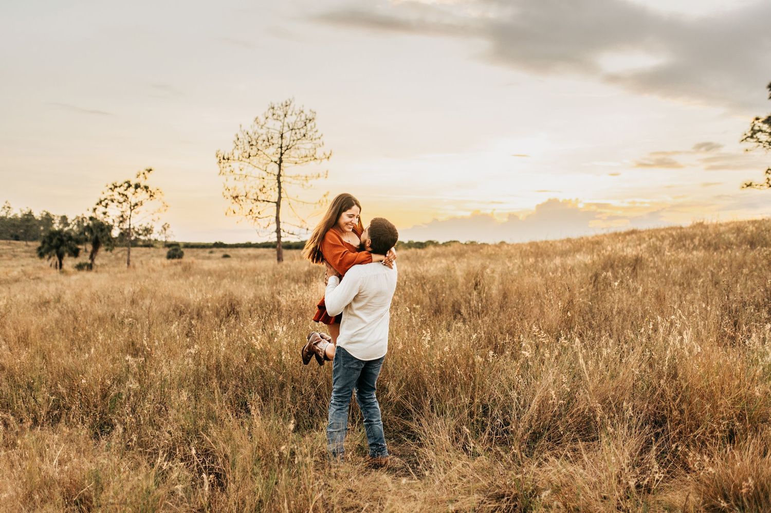 A romantic embrace in a golden field at sunset.