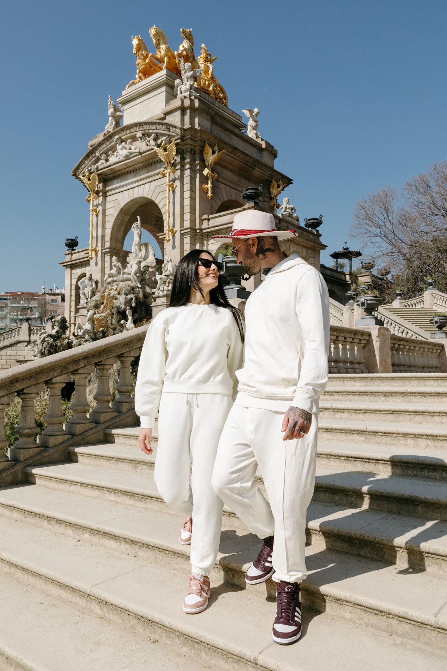 Two people in white outfits exploring an ornate architectural monument with golden details.
