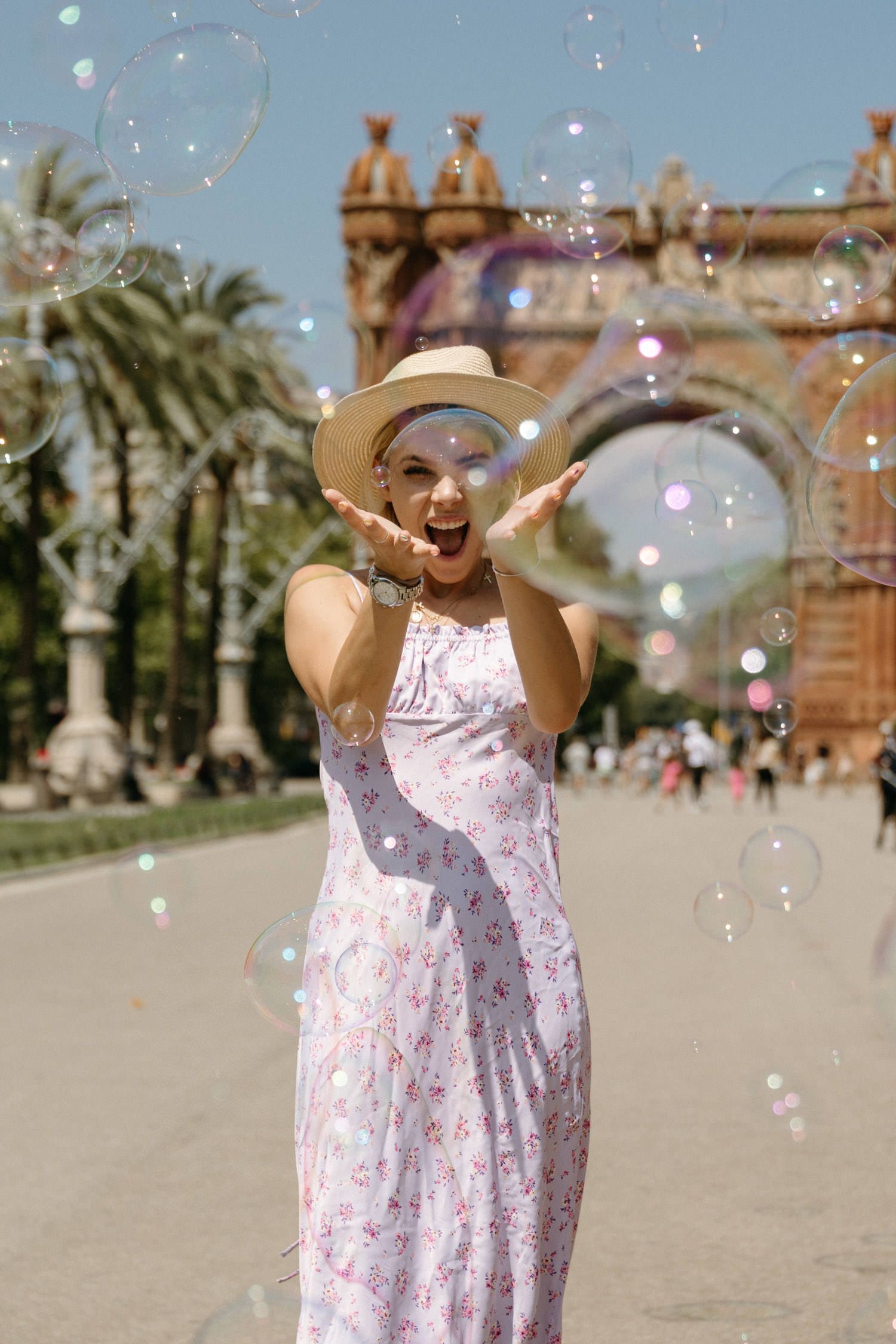 Celebratory moments with soap bubbles in front of Barcelona's Arc de Triomf on a sunny day.