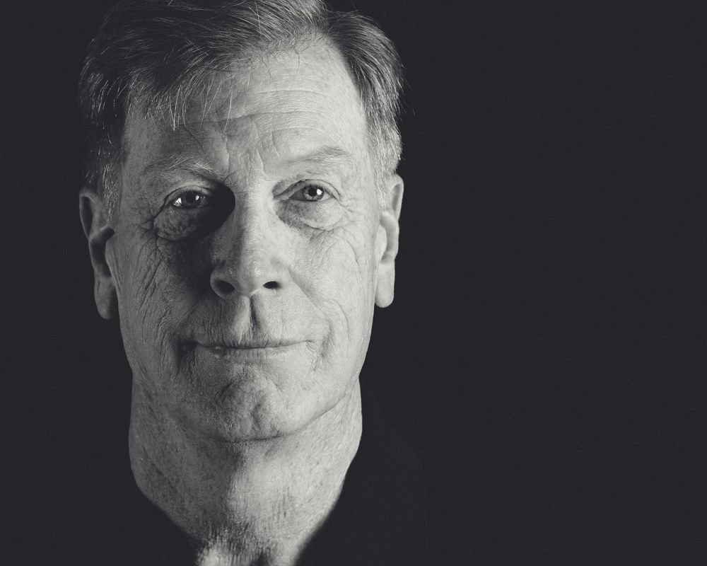 Black and white artistic portrait shot with dramatic side lighting and textural details.