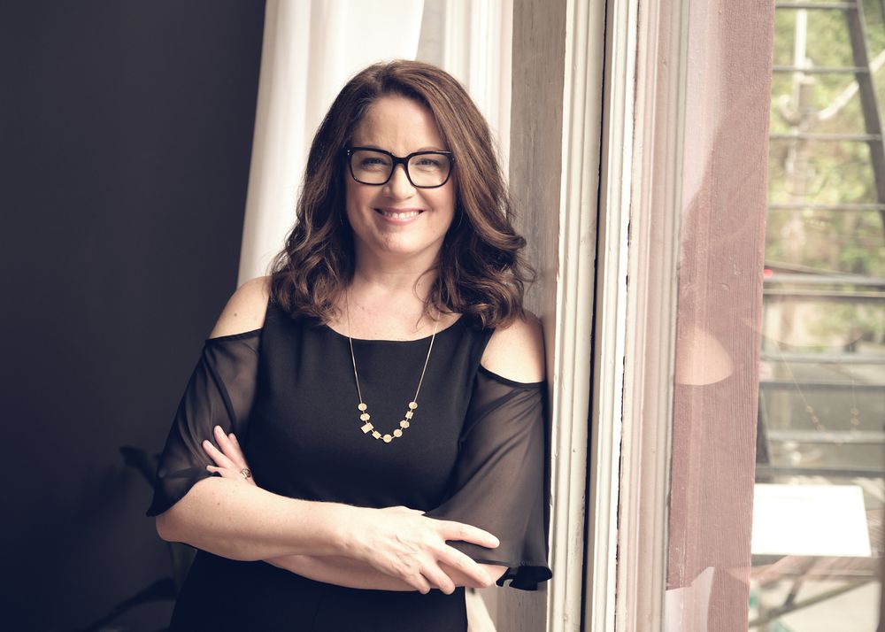Professional portrait session with black dress and modern eyewear by rustic wooden window frame.