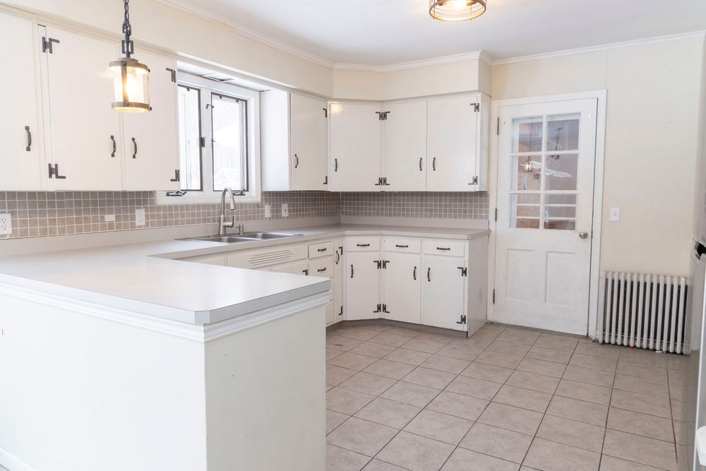 Contemporary kitchen with white cabinets and tiled flooring shown from multiple angles.