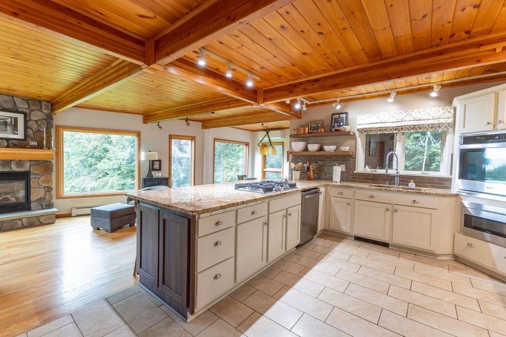Spacious kitchen with wooden ceiling and white cabinets showcased from various viewpoints.