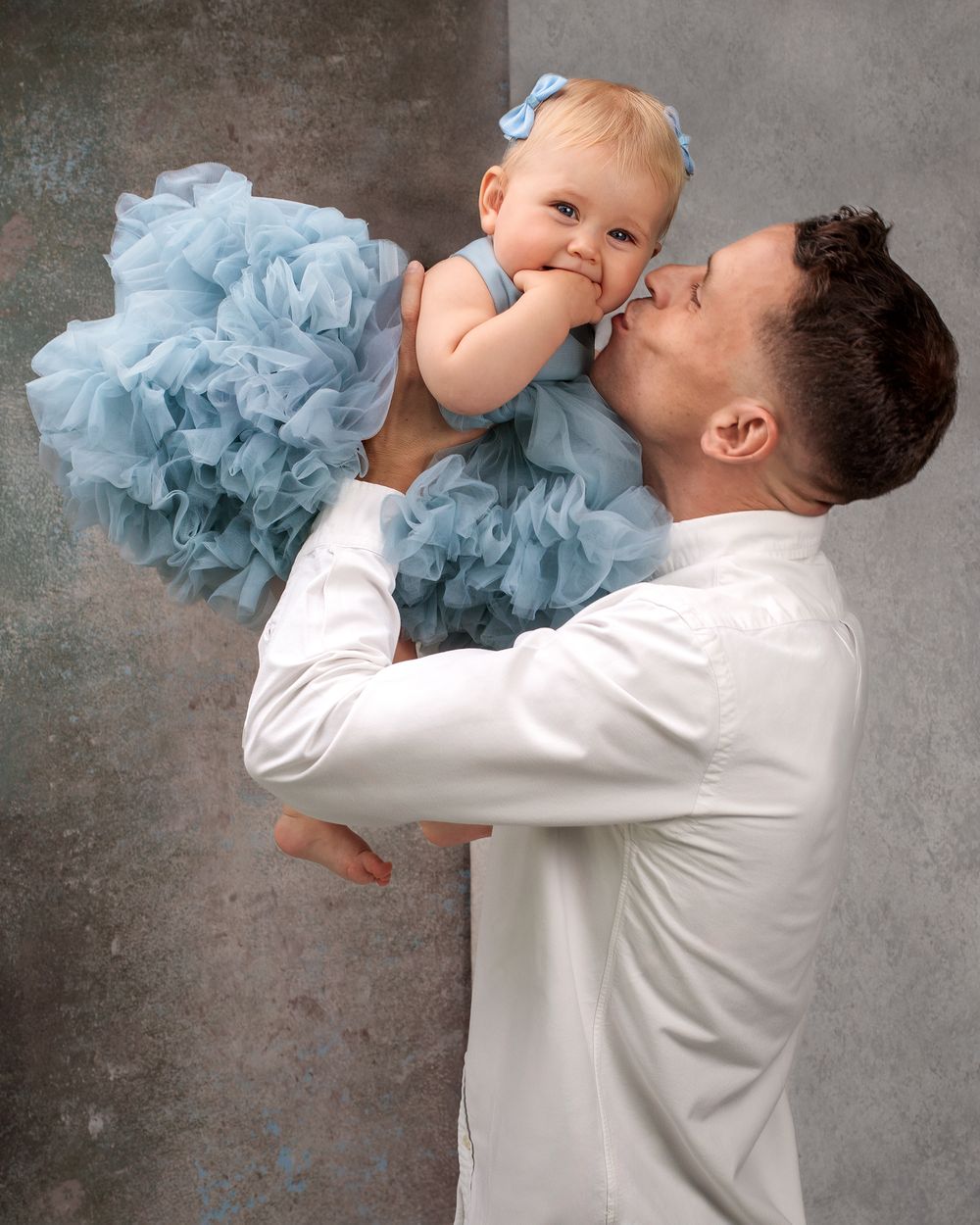 Father and daughter sharing a sweet kiss on the cheek during a studio session with Caz Captures.
