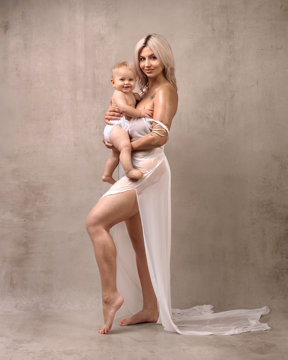 Fine art minimalistic motherhood photo: mum holding her baby, intimate studio lighting.