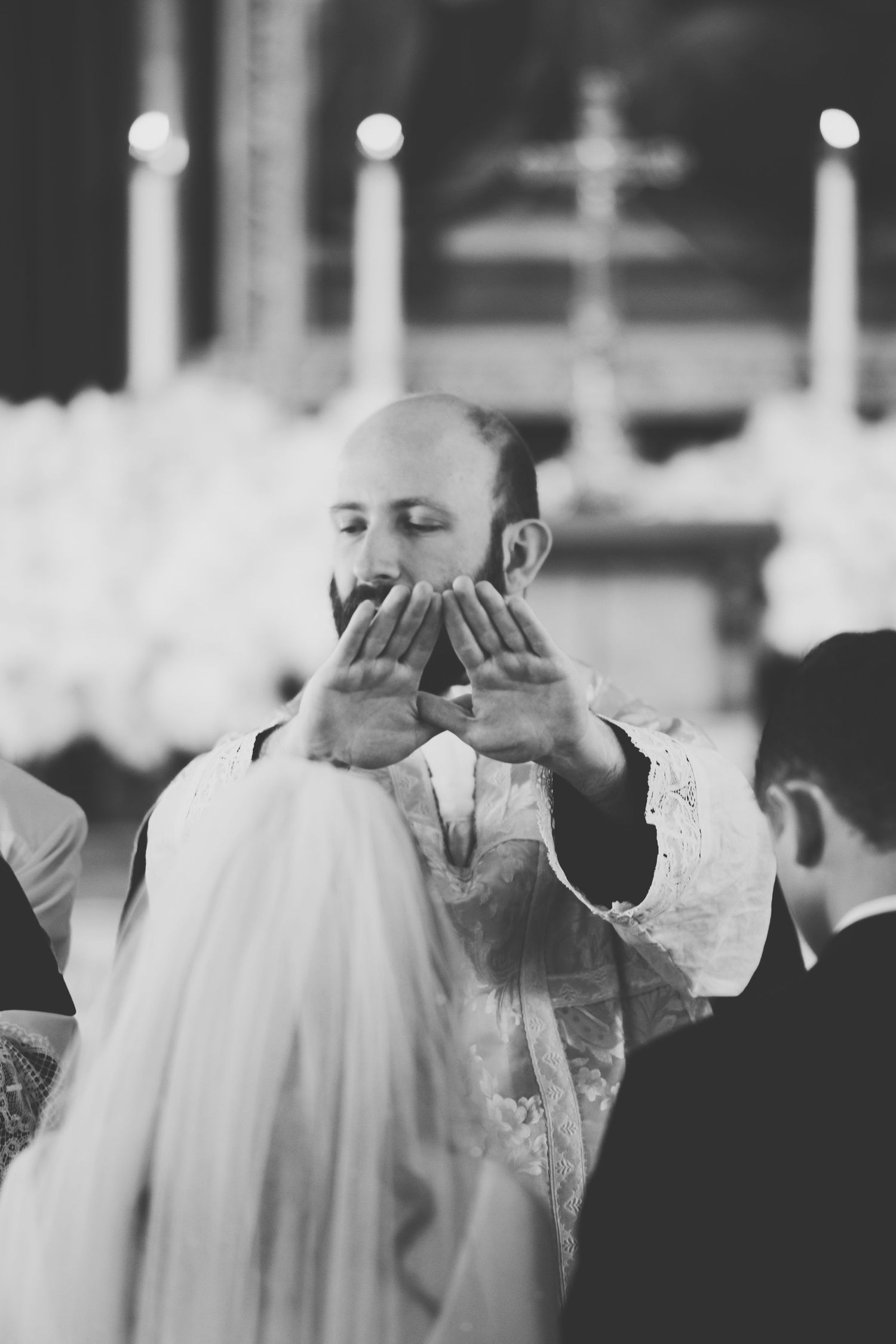 Black and white photo of Father Kent blessing a bride and groom at Holy Family Parish in Vancouver, BC.