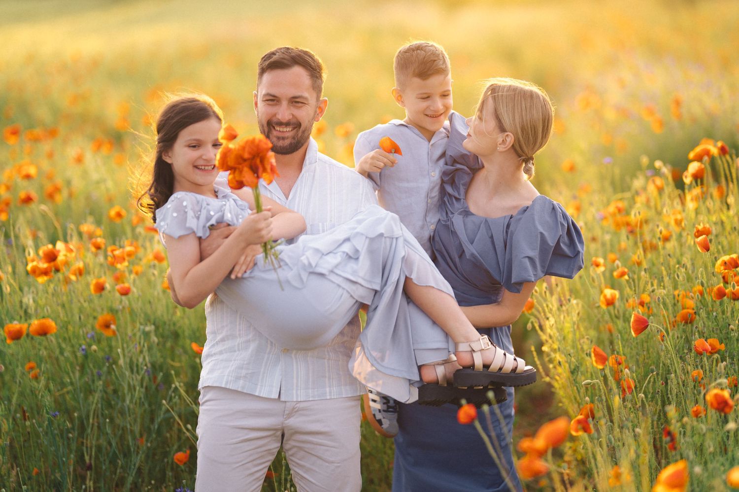 Happy family shares joyful moments together in a vibrant yellow and orange wildflower meadow at golden hour.