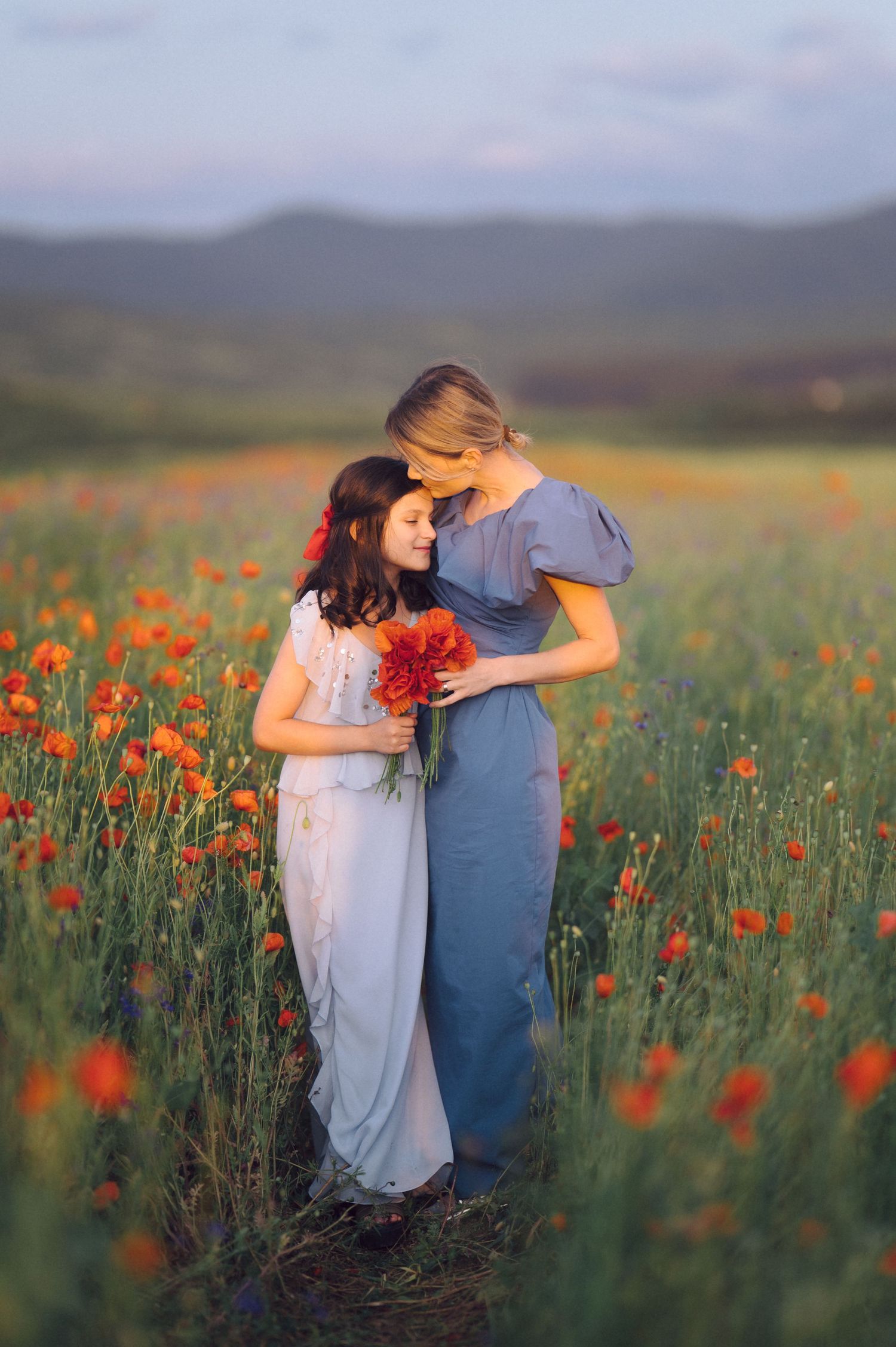 Couple embraces tenderly in a vibrant field of red poppies during golden sunset in countryside landscape.